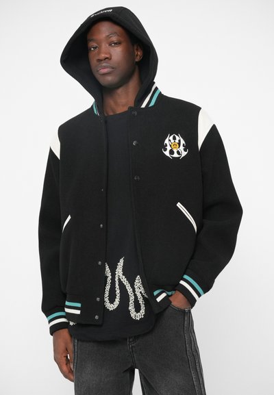 Schwarze Collegejacke mit türkisfarbenen und weißen Akzenten. Verfügt über ein Frontlogo, gestreifte Bündchen, Druckknopfverschluss und zwei Seitentaschen.