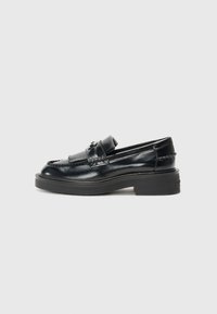 Mocassino in pelle nera con suola piatta e spessa, caratterizzato da un design cucito e una fascia rialzata e ripiegata nella parte frontale. Finitura liscia e lucida.