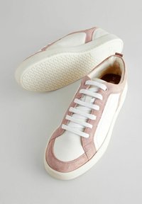 Fehér bőrsneakers rózsaszín velúr részletekkel. Jellemzője a lekerekített orr, lapos fehér fűzők, és texturált gumitalp, geometrikus mintával.