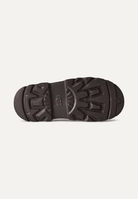 Sole di scarpe in gomma nera con un motivo testurizzato caratterizzato da scanalature e creste per una maggiore aderenza, logo in rilievo al centro e bordi arrotondati.