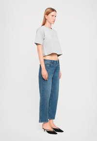 Harmaa lyhythihainen crop-top, siniset suorat farkut ja mustat kärkitossut. Sileä kangas ja tiukka muotoilu.