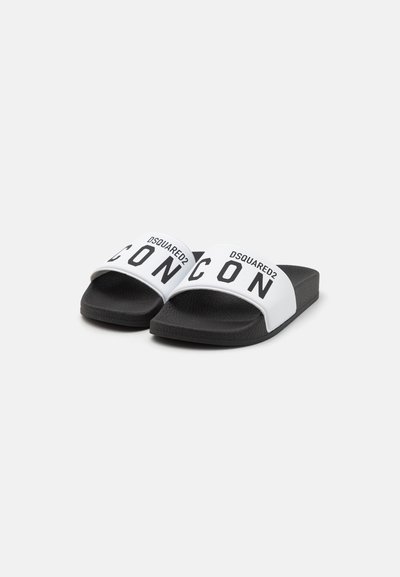 Sandali slide in bianco e nero con cinturini larghi; testo "DSQUARED2" e "ICON" in nero su bianco. Soletta texturizzata e suola piatta.