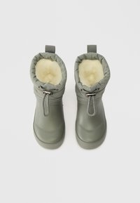Bottes en cuir gris imperméables avec une doublure en fourrure douce de couleur crème, un revers élastique et un cordon ajustable pour un maintien sécurisé.