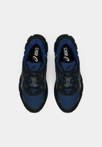 Μαύρα και μπλε αθλητικά παπούτσια με δικτυωτή επάνω επιφάνεια, ενισχυμένο επάνω μέρος στη μύτη και υφασμάτινη σόλα με ανάγλυφες λεπτομέρειες και ανακλαστικές λεπτομέρειες στις πλευρές.