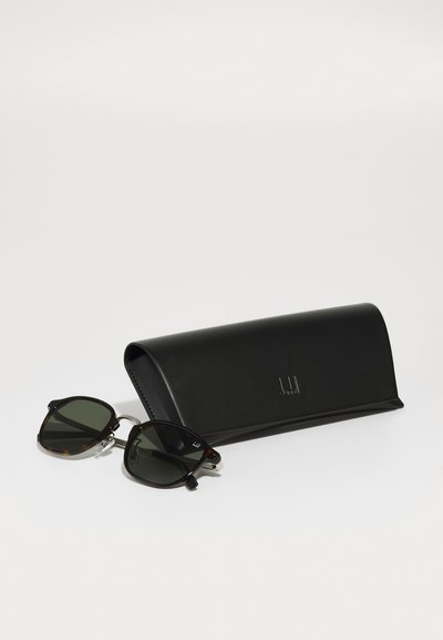 Sunglasses with dark green lenses and a tortoiseshell frame next to a black leather case with a smooth texture and embossed logo.