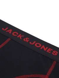 Boxer breves negros con una cinturilla elástica roja que presenta el texto "JACK & JONES". Detalles de costura en hilo rojo sobre las aberturas de las piernas.