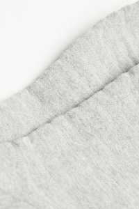 Tessuto grigio chiaro con una texture morbida e un motivo di tessitura sottile, caratterizzato da un bordo arrotolato per una finitura ordinata.