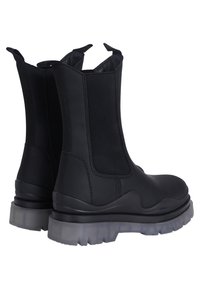 Botas Chelsea negras con paneles elásticos laterales y lengüetas de tirón. Suela de goma texturizada con acento transparente. Exterior de cuero suave.