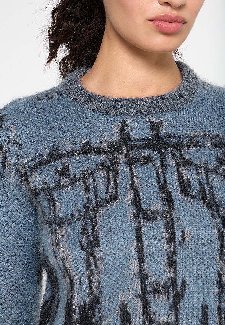 Hellblauer Strickpullover mit einem strukturierten Muster in Schwarz und Grau. Runder Halsausschnitt, weicher Stoff und lockere Passform.