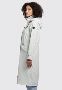 Light gray waterproof parka with a detachable hood, side pockets, and drawstring accents. Features a logo patch on the upper arm.