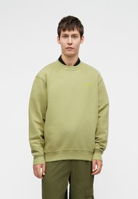Olivno zelen sweatshirt iz mehkega blaga, z okroglim izrezom, rebrastimi manšetami in majhnim izvezenim logotipom spredaj.