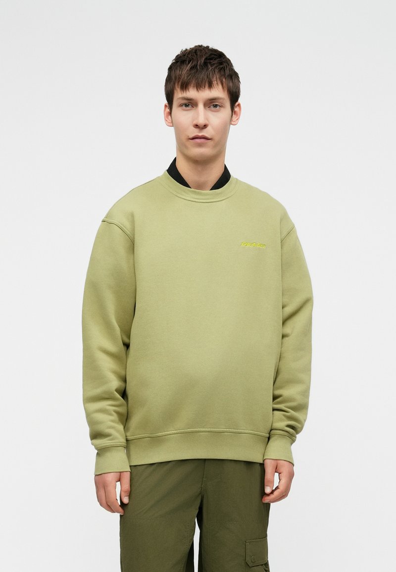 Olivno zelen sweatshirt iz mehkega blaga, z okroglim izrezom, rebrastimi manšetami in majhnim izvezenim logotipom spredaj.