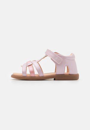 Pink leather sandals with a strappy design, adjustable Velcro strap, and a brown rubber sole. Features cutouts on the heel and toe areas.