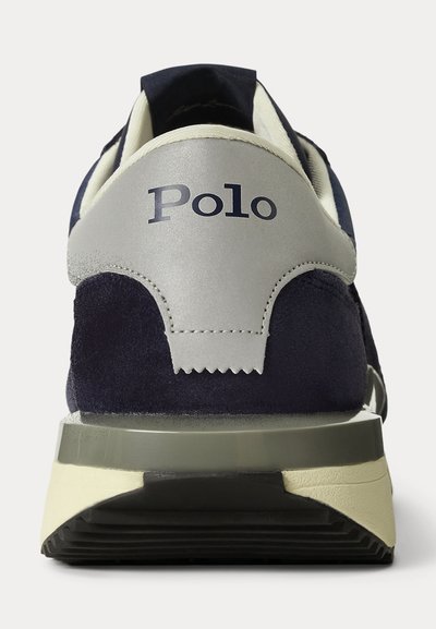 Tamsiai mėlynos ir pilkos spalvos Polo sportinio batelio nugaros vaizdas, rodantis kulną su užrašu „Polo“ ir storu guminio pado sluoksniu.