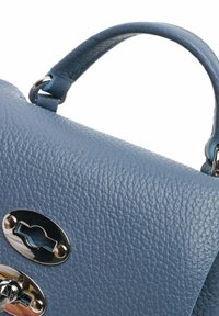 Sezione di borsa in pelle blu texturizzata con manico e serratura in metallo argentato su sfondo bianco.