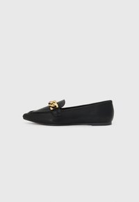 Svarte skinnloafers med spiss tå, med en dekorativ gullkjedeakzent foran og flat såle. Minimalistisk design.
