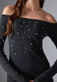 Schwarzes schulterfreies Oberteil aus geripptem Stoff, verziert mit verstreuten Strasssteinen, mit langen Ärmeln und figurbetonter Silhouette.