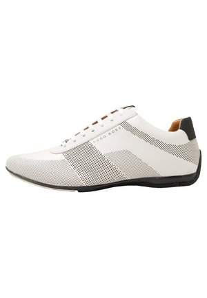 Weißer Low-Top-Sneaker mit schwarzem Punktemuster, weißen Schnürsenkeln, schwarzer Fersenschlaufe und "Hugo Boss" Logo an der Seite.