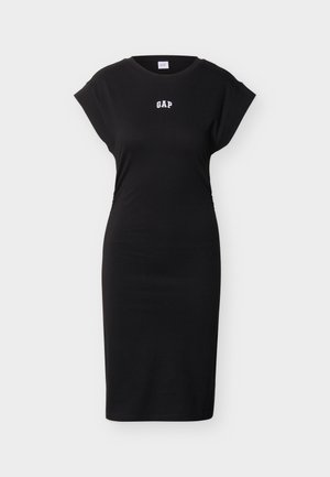 Μαύρο εφαρμοστό φόρεμα μήκους μέχρι το γόνατο με κοντά μανίκια και λευκό λογότυπο "GAP" στο κέντρο του στήθους, πάνω σε απλό φωτεινό φόντο.