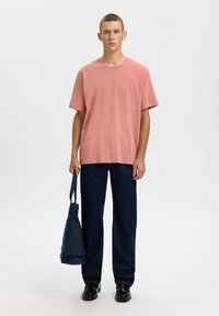 Ανοιχτό ροζ κοντομάνικο μπλουζάκι σε συνδυασμό με σκούρο μπλε τζιν με φαρδιά πόδια. Το σύνολο ολοκληρώνεται με μια ναυτικό τσάντα ώμου και μαύρα παπούτσια.