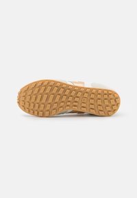 Sneakers med en strukturert gummisåle i gummifarge, med en hvit mesh-overdel og brune semskede detaljer. Designet for godt grep og støtte.