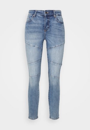 Jeans skinny em denim azul claro com detalhes de painéis. Apresentam uma cintura média, bolsos frontais e desbotamento subtil no tecido.