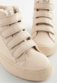 Beige High-Top-Sneaker mit drei Klettverschluss-Riemen, strukturiertem Gummilaufsohle und einem weichen Fellfutter. Verfügt über funkelnde Akzente auf den Obermaterialien.