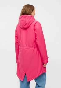 Vattentät rosa regnjacka med huva, justerbar midja och en rundad nederkant. Har långa ärmar och en slät, glossig yta.