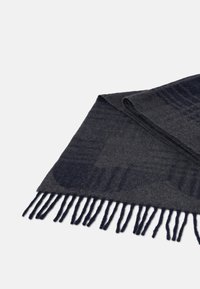 Tmavě šedá vlněná šála s jemným vzorem, zakončená dlouhými texturovanými třásněmi po okraji. Měkká textura, obdélníkový tvar.