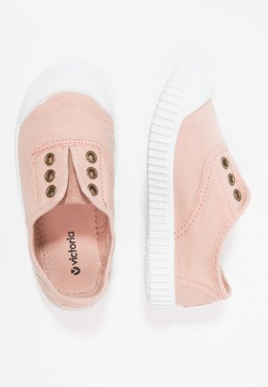 Pink canvas slip-on shoes with a white rubber sole, featuring two bronze eyelets on each side. Smooth texture, minimalist design.
