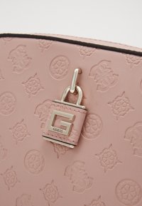 Rosa strukturierte Tasche mit geprägten Blumenmustern, silberner Hardware und einem Logo-Verschlussakzent. Glatte Oberfläche mit einem dezenten Schimmer.