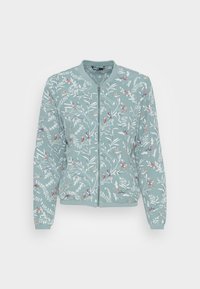 Lichtblauwe bomberjack met ritssluiting, versierd met witte bladeren en kleurrijke vogelpatronen, met ribgebreide kraag, manchetten en zoom, weergegeven tegen een witte achtergrond.