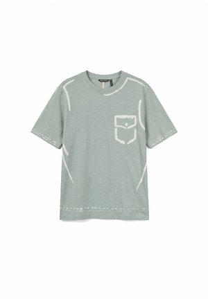 T-shirt vert clair à manches courtes avec contours blancs style croquis et design avec poche avant, posé à plat sur fond blanc.