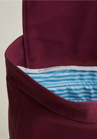 Burgundy tygväska med en bred öppning, med ett blått och vitt randigt foder, slät textur och rena sömmar.