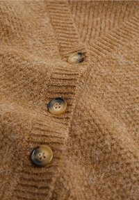Cardigan en maille marron, composé d'un mélange de laine texturée, design à col en V, avec trois boutons ronds transparents soulignés d'accents foncés.
