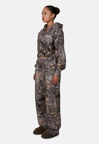 Camo hoodie en broek set in bruin en grijs tinten. Beschikt over een capuchon met trekkoord, een elastische tailleband en door de natuur geïnspireerde patronen.