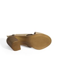 Beiger Leder-Hochhackenschuh mit runder Zehenpartie, strukturierter Gummisohle und dicker Absatz. Sichtbare Nahtdetails entlang der Kante.