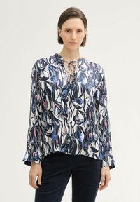 Blouse à manches longues en tissu léger avec un motif abstrait bleu marine, blanc et rose, dotée d'un décolleté noué et d'une coupe décontractée.