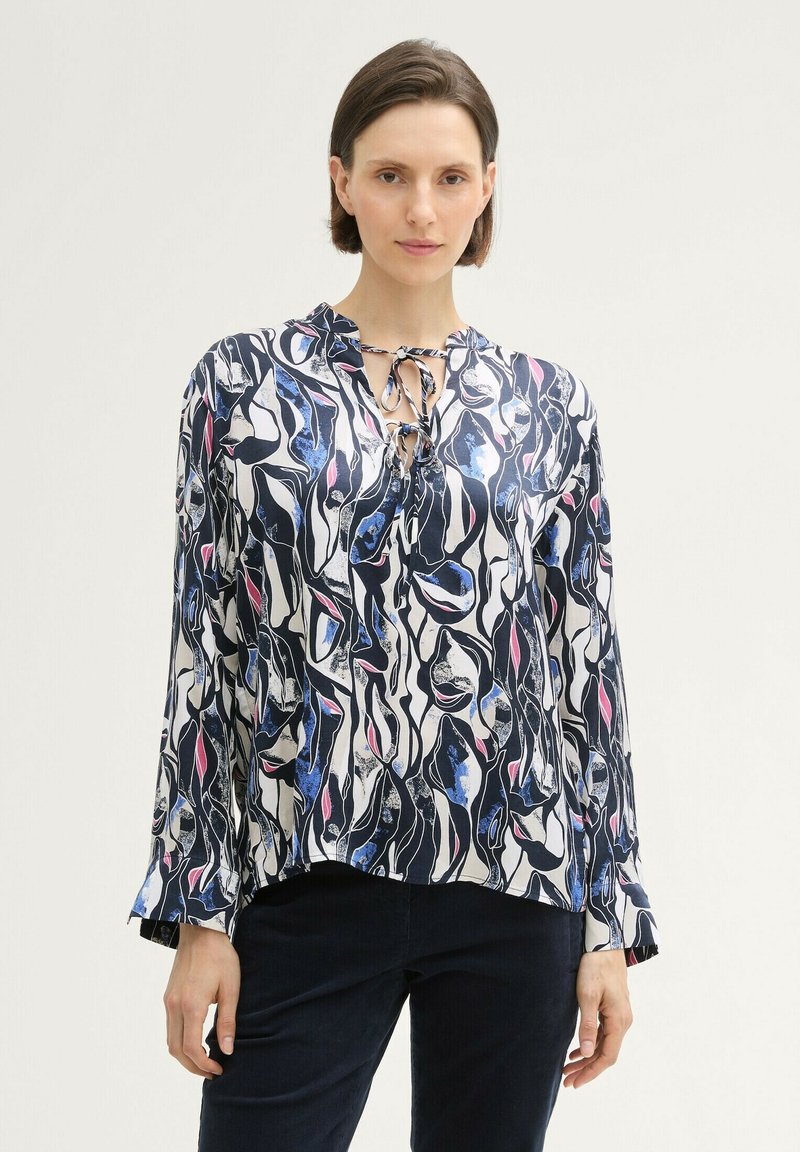 Blouse à manches longues en tissu léger avec un motif abstrait bleu marine, blanc et rose, dotée d'un décolleté noué et d'une coupe décontractée.