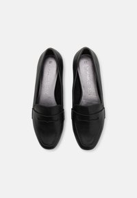 Juodi slip-on loaferiai su lygiu odiniu paviršiumi, apvaliu pirštu ir dekoratyvine siuvinėta juosta viršuje. Viduje yra sidabrinė pado dalis.