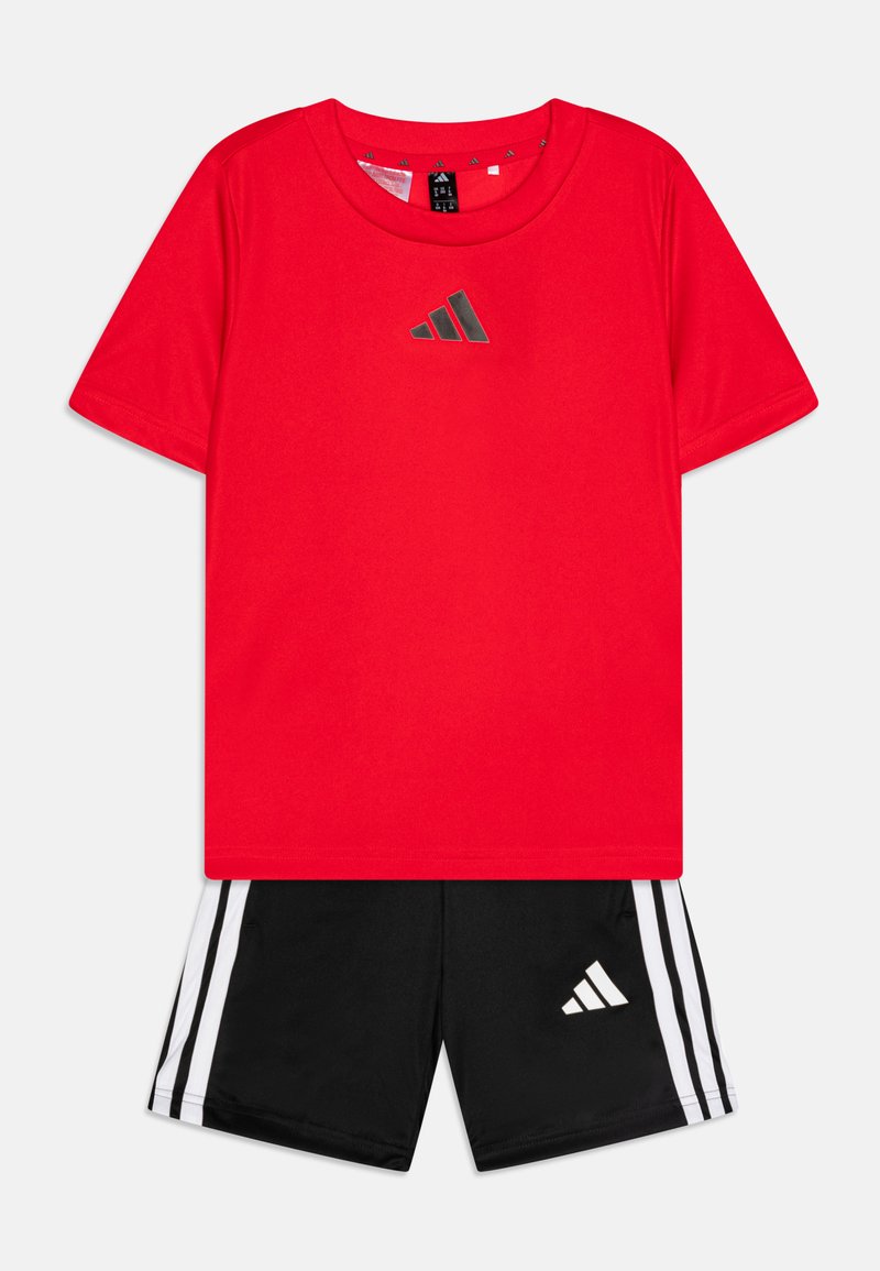 Czerwony sportowy t-shirt z krótkim rękawem z odblaskowym czarnym logo, w zestawie z czarnymi szortami z trzema białymi paskami i pasującym logo.