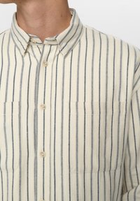 Roomkleurig overhemd met knopen en marineblauwe horizontale strepen, met een opstaande kraag, twee borstzakken en een zachte, gestructureerde stof.