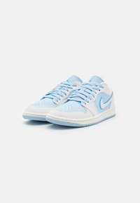 Sneakers blu chiaro e bianchi realizzati in materiale in pelle e tessuto, con una punta perforata, lacci piatti e un logo a swoosh sui lati.