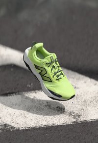 Neon green running shoe with a textured mesh upper, black detailing, and a white speckled sole. Features reinforced toe protection.