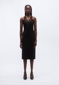 Must kleit V-kaelusega ja vertikaalsete triipudega kehaosa peal. Liibuv siluett, põlveni ulatuv, minimalistlik disain, kombineeritud teravate kontsadega.