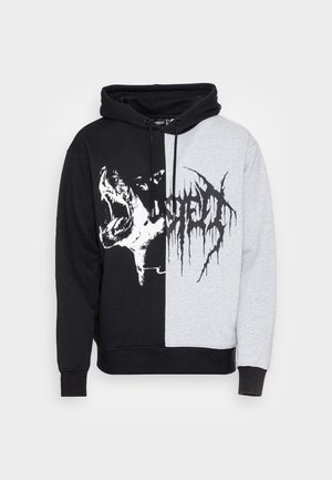 Bluza z kapturem podzielona na czarną i szarą część, z grafiką ryczącego psa po czarnej stronie i abstrakcyjnym czarnym tekstem po szarej stronie.