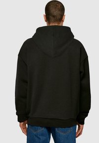 Sorte hættetrøje med en afslappet pasform, blød tekstur og ribbede manchetter. Bagsiden har en central søm og minimal detaljer.