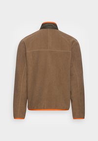 Brun fleecejacka med grön krage och orange detaljer. Har en avslappnad passform och rak nederkant, med minimala sömnadsdetaljer.