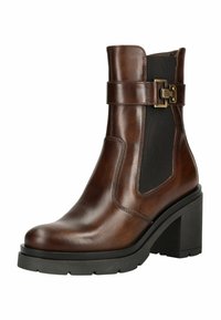 Bottine en cuir marron avec un talon épais noir, panneau élastique sur le côté et sangle décorative avec boucle en laiton sur fond blanc.