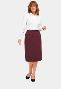 Bordeaux knielange rok met een elastische tailleband en zijzakken, gecombineerd met een witte blouse en zwarte flats.